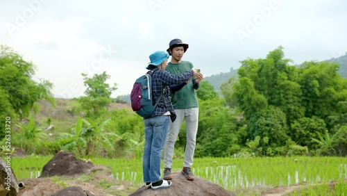 4K, Young Asians, walking to find a soft field that has just been planted, The two of them were thrilled to see the beautiful green rice fields, ready to pick up the phone to take a photo. photo