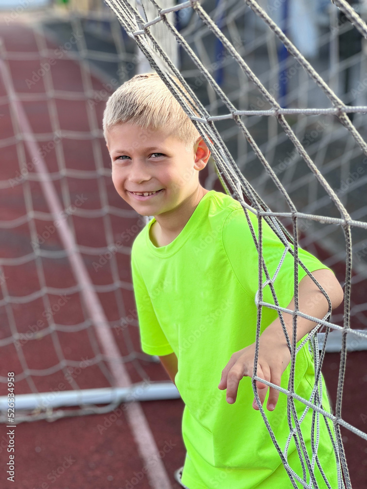 portrait of happy boy sitting on football field. sports section. portrait of happy boy sitting on football field. sports section.