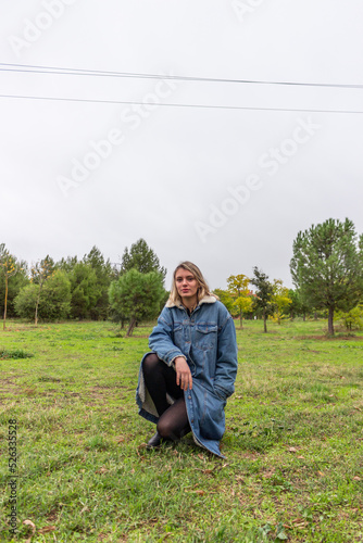 Beautiful blonde girl serious in the green nature with a blue jean coat © JuanDiego