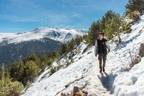 Caucasian man walking in the middle of a snowy of a pine forest