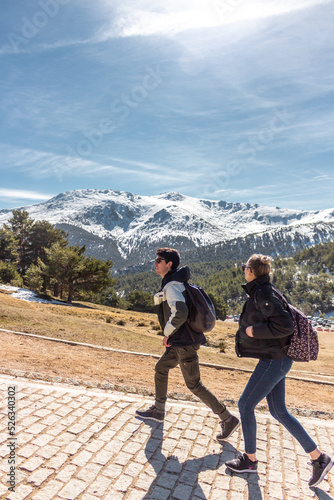 Two friends walking with sunglasses with the snowy mountains in the background