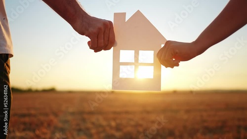 paper house happy family. friendly family hands holding paper house the glare of the sun shine through the window a beautiful sunset. mortgage lifestyle business construction concept. house dreams