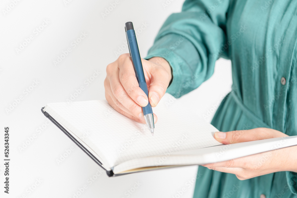 ノートにメモを書く女性の手元 ノートにメモを書く女性の手元