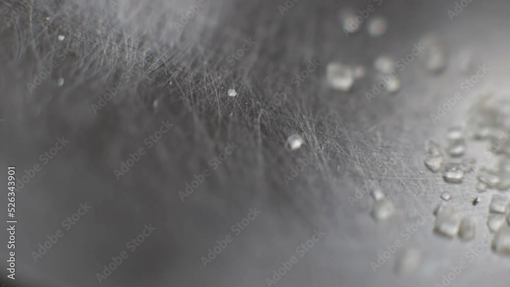 Shallow focus shot of crystals of sugar falling on a stainless steel surface Shallow focus shot of crystals of sugar falling on a stainless steel surface
