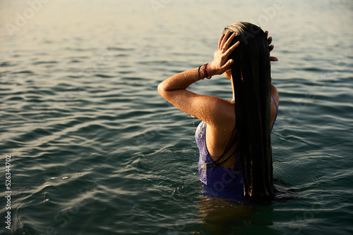 Canvas Print young girl wearing a purple swimming suite taking a morning bath on the mediterr