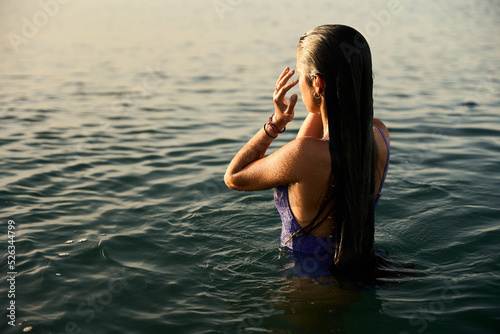 Photography young girl wearing a purple swimming suite taking a morning bath on the mediterr