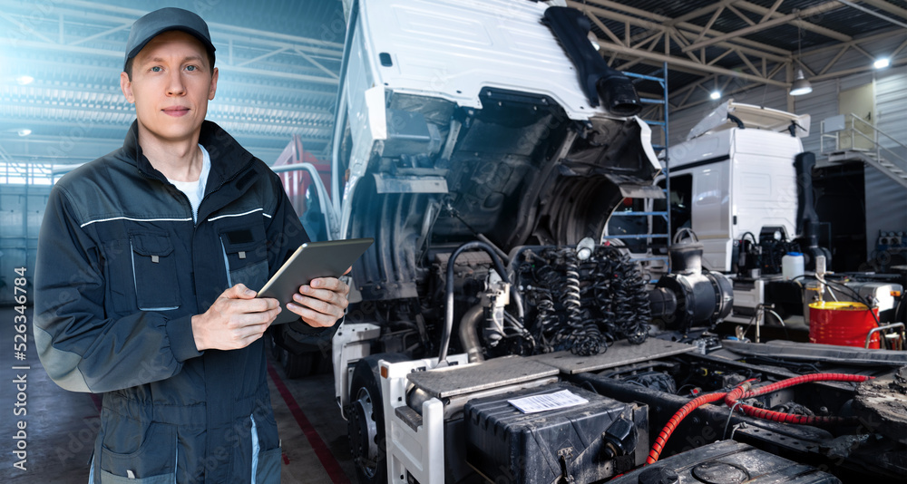Serviceman with digital tablet on the background of the truck in the garage Serviceman with digital tablet on the background of the truck in the garage