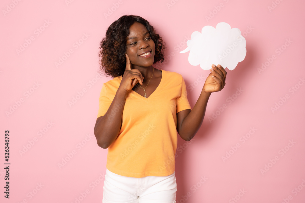 Portrait of funny pretty dark skin lady holding paper cloud mind thinking over creative dialogue answer doubtful wearing orange t-shirt isolated pink background Portrait of funny pretty dark skin lady holding paper cloud mind thinking over creative dialogue answer doubtful wearing orange t-shirt isolated pink background