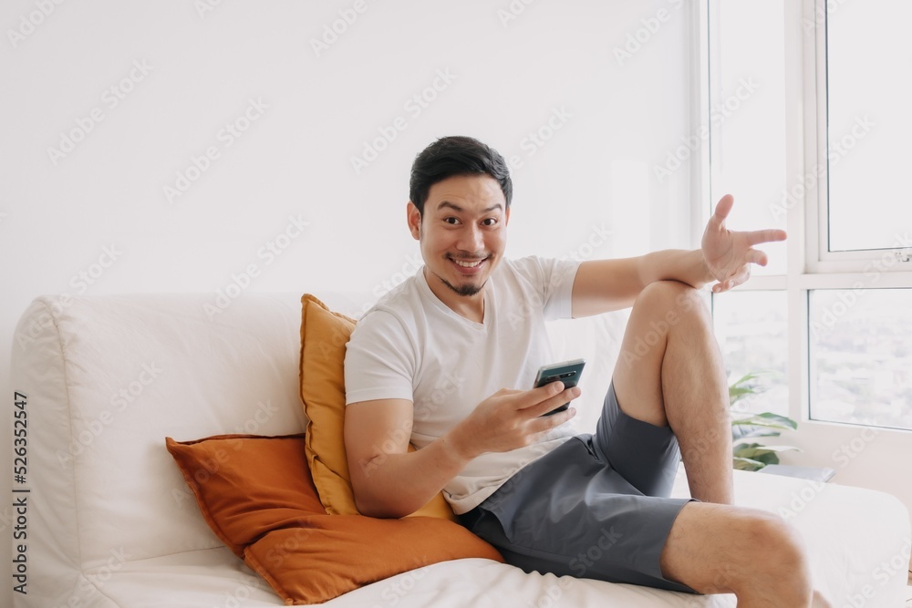 Happy asian man use smartphone in the living room for advertising content. Happy asian man use smartphone in the living room for advertising content.