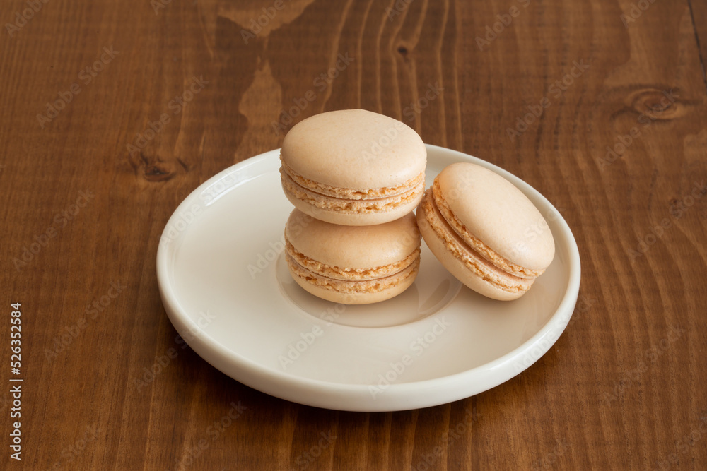 Three Sweet vanilla white macarons on a dark wood background. Tasty colourful macaroons. Three Sweet vanilla white macarons on a dark wood background. Tasty colourful macaroons.