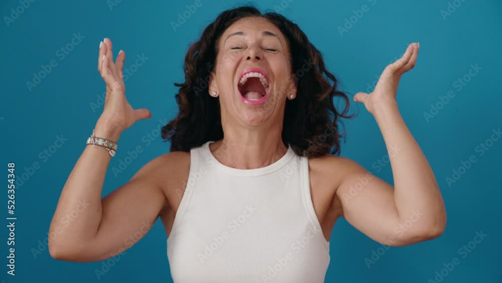 Middle age woman standing with surprise expression over isolated blue background Middle age woman standing with surprise expression over isolated blue background
