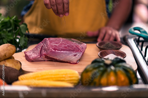 Photography Hands seasoning a piece of meat with black pepper