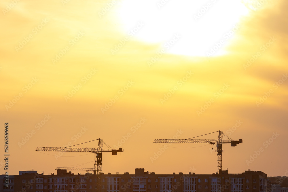 silhouettes of building cranes in the evening sky against the backdrop of sunset. urban building industry