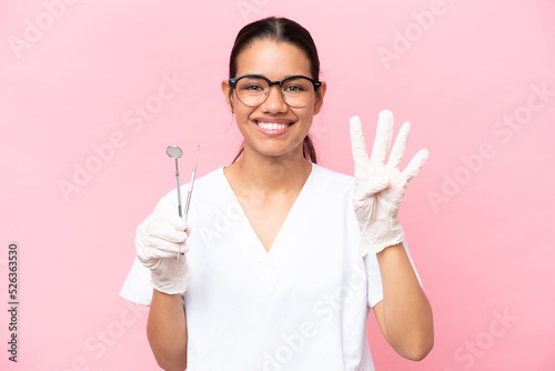 Dentist Colombian woman isolated on pink background happy and counting four with fingers