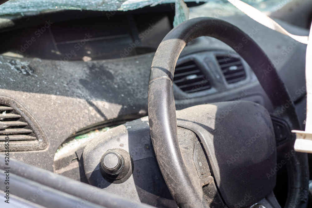 Close-up of the steering wheel of a car after an accident. The driver's airbags did not deploy. Soft focus. Broken windshield with steering wheel. Vehicle interior. Black dashboard and steering wheel. Close-up of the steering wheel of a car after an accident. The driver's airbags did not deploy. Soft focus. Broken windshield with steering wheel. Vehicle interior. Black dashboard and steering wheel.