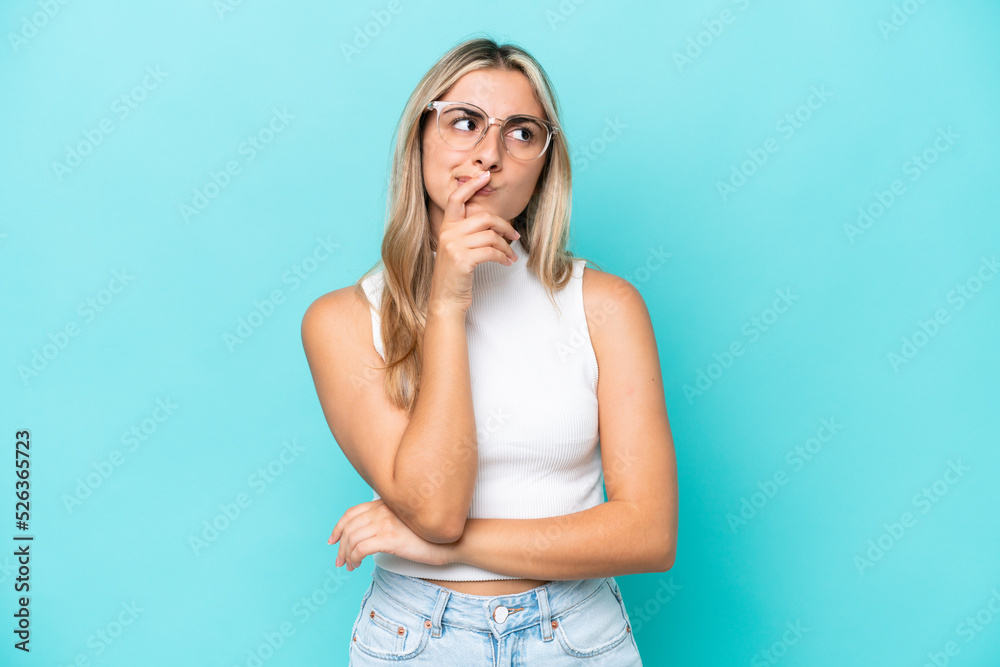Young caucasian woman isolated on blue background having doubts and with confuse face expression Young caucasian woman isolated on blue background having doubts and with confuse face expression