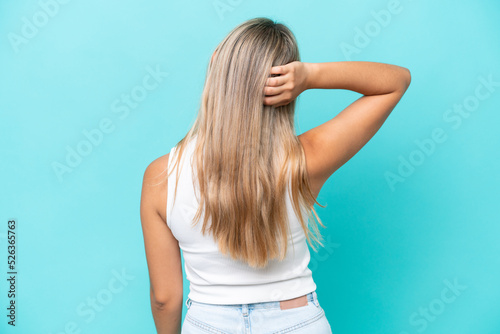 Young caucasian woman isolated on blue background in back position and thinking