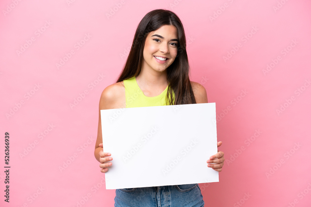 Young Brazilian woman isolated on pink background holding an empty placard with happy expression Young Brazilian woman isolated on pink background holding an empty placard with happy expression