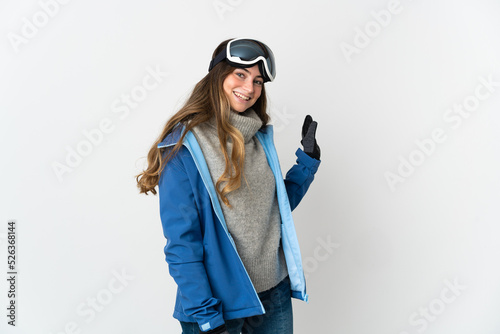 Skier girl with snowboarding glasses isolated on white background saluting with hand with happy expression