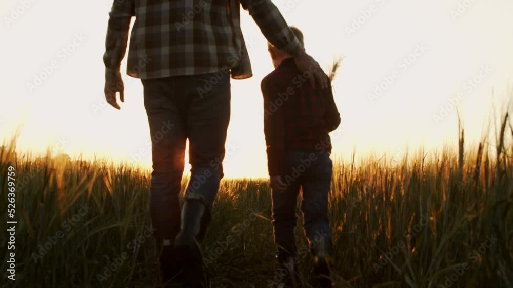 Farmer and his son in front of a sunset agricultural landscape. Man and a boy in a countryside field. Fatherhood, country life, farming and country lifestyle concept.