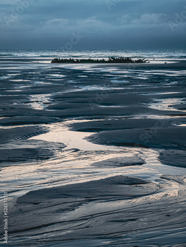 Small sandbanks lead the way to a shipwreck at low tide