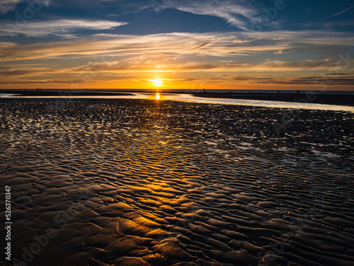 Ripples in the sand at low tide during dramatic sunset