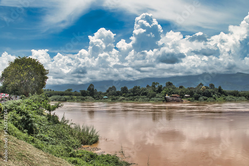 View over the Mekong River from the Buddhist temple Wat Along Silawat, province of Bueng Kan, Thailand. Cloudy sky over the mountains of Laos. 