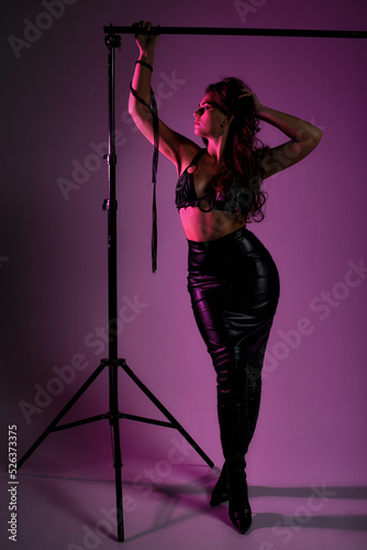 beauty woman in latex skirt on pink background, mistress