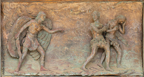 MONOPOLI, ITALY - MARCH 6, 2022: The bronze relief  Expulsion of Adam and Eve from Paradise the  on the gate of church Chiesa di Sacro Cuore by Wolfgang Stempfele from year 2002.