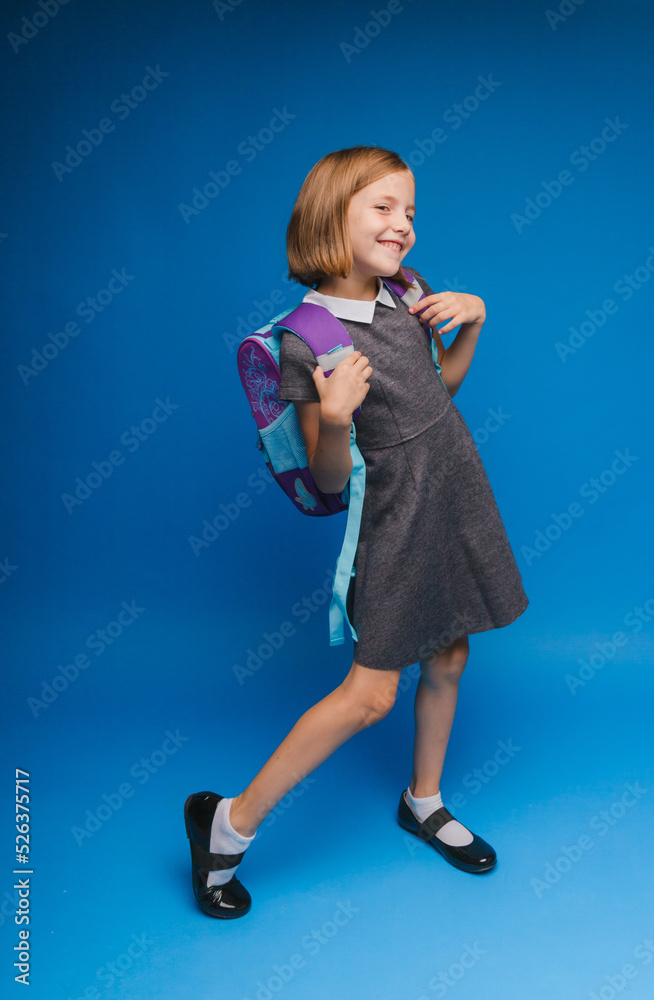Back to school. A schoolgirl with a school bag on an isolated blue studio background. a little girl is holding a backpack. Back to school. A schoolgirl with a school bag on an isolated blue studio background. a little girl is holding a backpack.