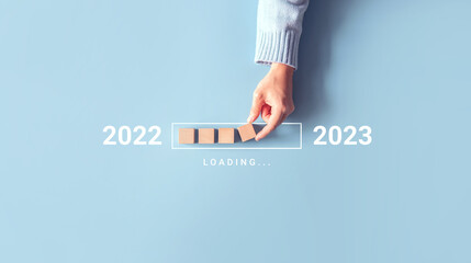 Loading new year 2022 to 2023 with hand putting wood cube in progress bar. Start new year 2023 with goal plan, goal concept, strategy.