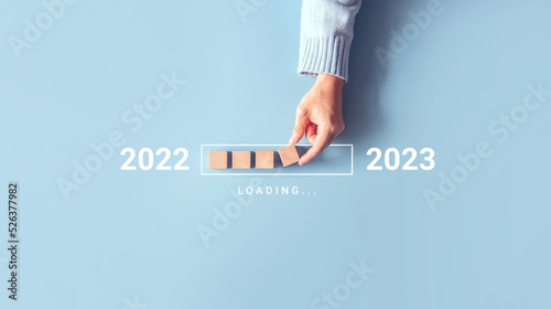 Loading new year 2022 to 2023 with hand putting wood cube in progress bar. Start new year 2023 with goal plan, goal concept, strategy. photo