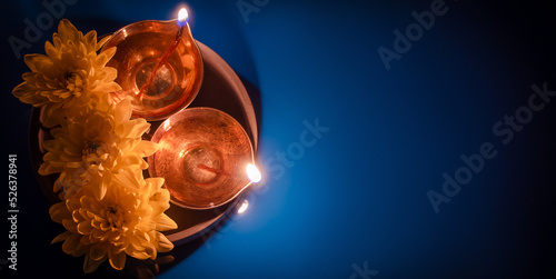 Diwali Indian holiday. Traditional diya oil lamps and yellow flowers on blue background. Celebrating festival of light.