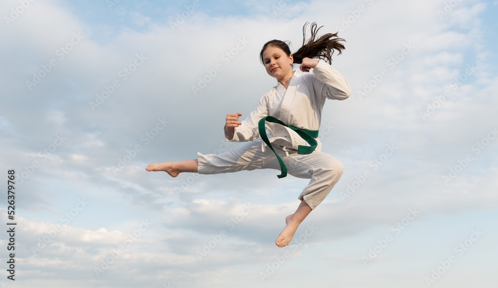 judo concept. teen girl practicing judo. girl judo fighter jump on sky background