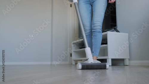 Woman cleaning living room with modern bagless upright vacuum cleaner. Technology, housework, routine and housekeeping concept photo