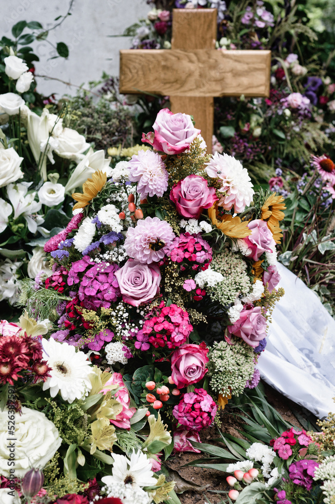 colorful flowers on a grave with a wooden cross after a funeral