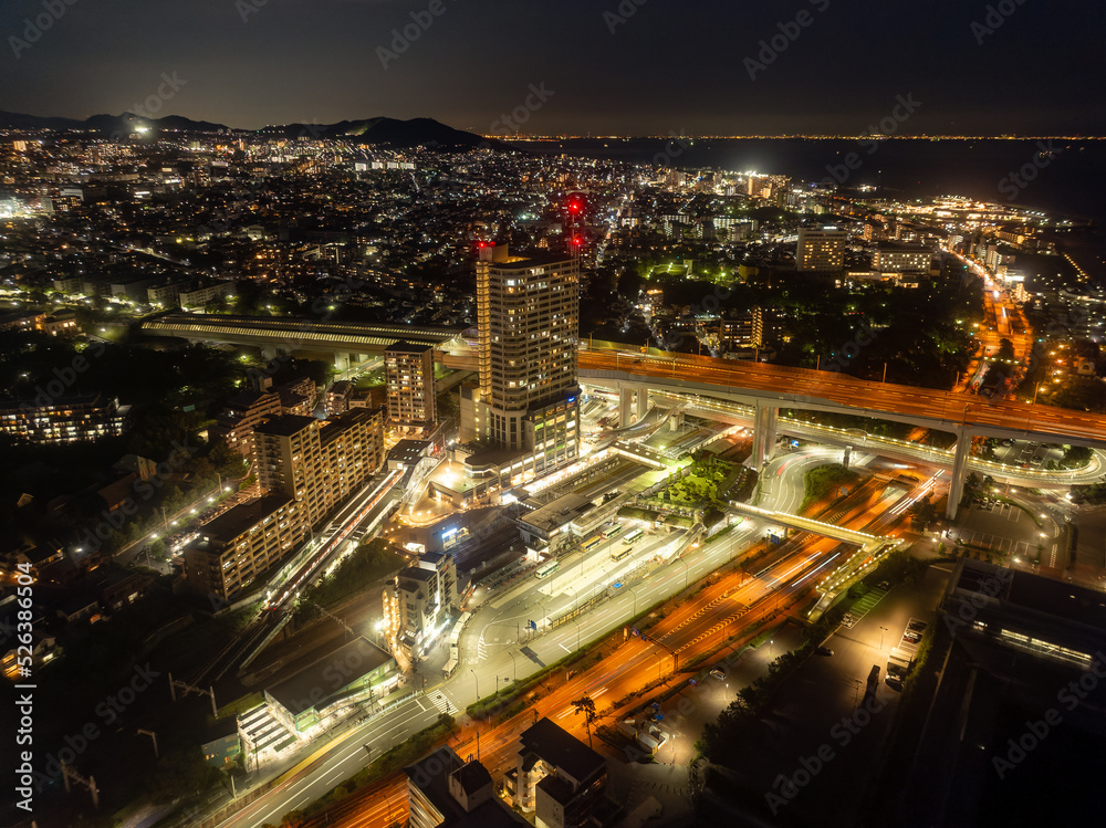 Naklejka premium Residential tower stands above major roads through city at night
