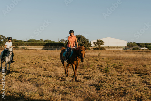 girl riding a brown pony across a meadow with laughter © Samuel Perales