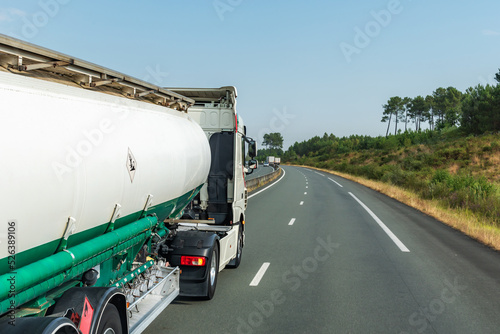 Fuel tanker truck driving on a highway, side view.