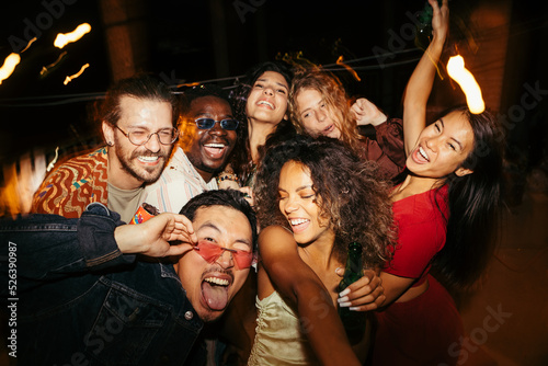 A Group of tipsy friends has a blast at the summer roof party at night. photo