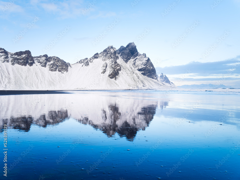 Stokksness, Vestrahorn National Park, Iceland. Wide beach with black volcanic sand. Reflections on the seashore at high tide. View of Iceland's nature in winter time.
