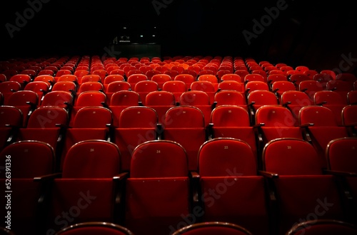 Empty theatre with red seats in low light stock photo