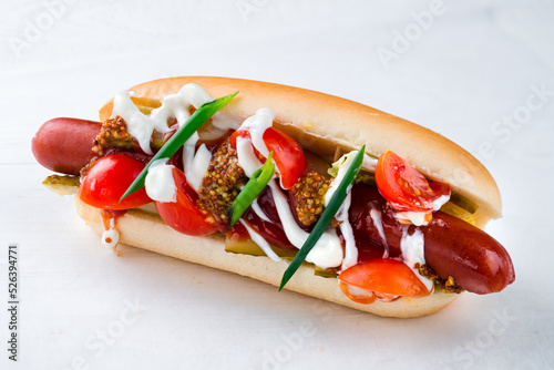 Foto hot dog with sausage, tomatoes, pickles and mustard on a white background