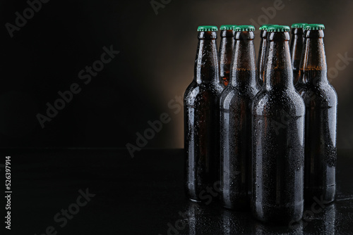 Many bottles of beer on table against dark background, space for text