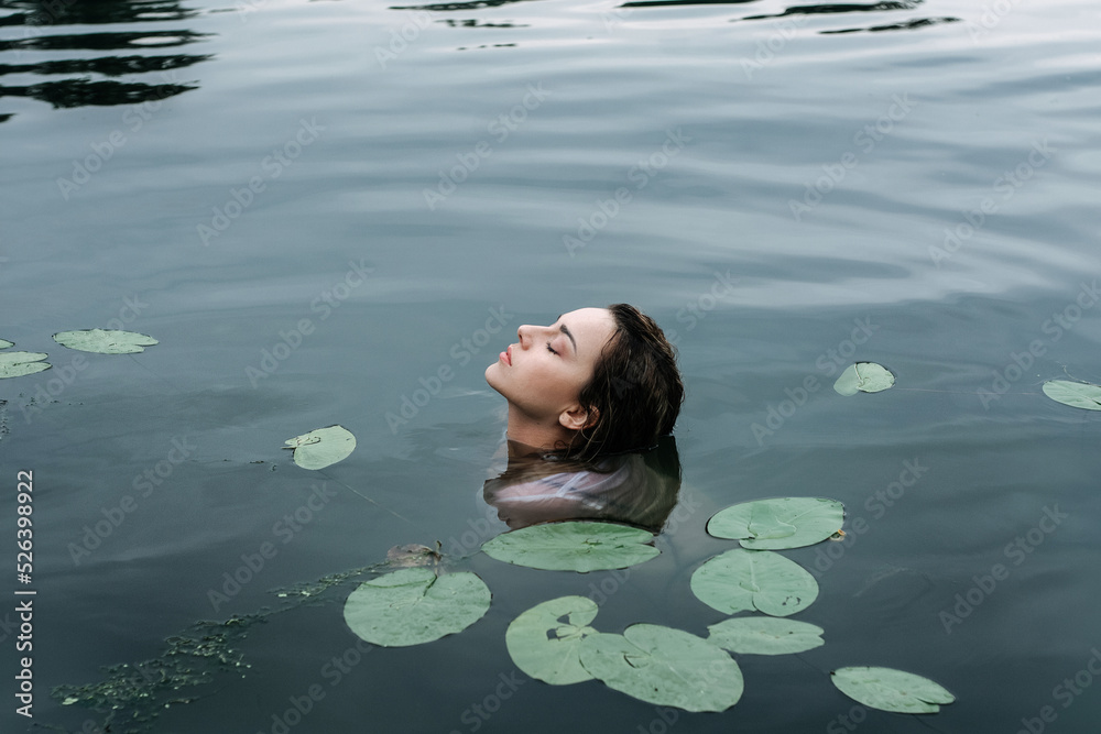 Attractive mysterious girl like a mermaid swimming in the lake in a ...