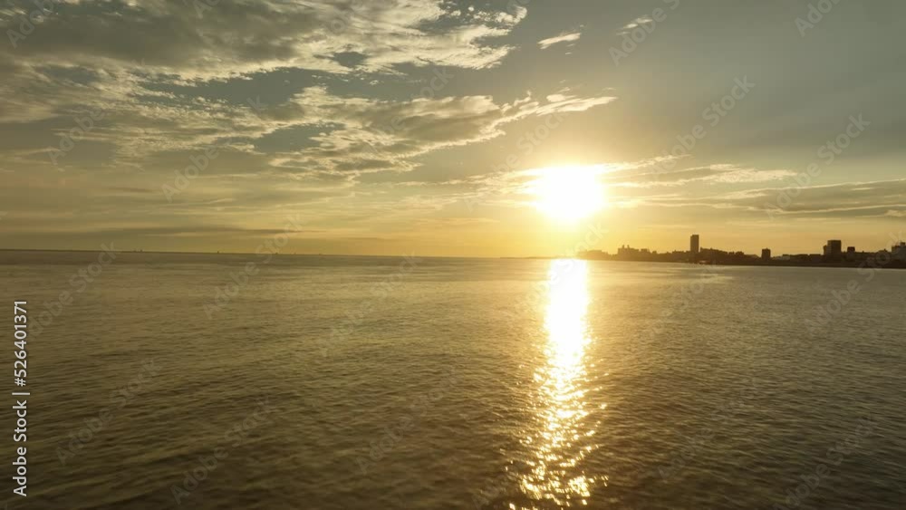 Flying low over small waves toward setting sun reflecting off calm water Flying low over small waves toward setting sun reflecting off calm water