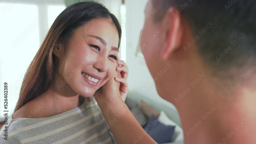An Asian young happy smiling married couple is enjoying time together is hugging as a sign of love at home. Women have an embarrassing attitude while making eye contact with his boyfriend An Asian young happy smiling married couple is enjoying time together is hugging as a sign of love at home. Women have an embarrassing attitude while making eye contact with his boyfriend