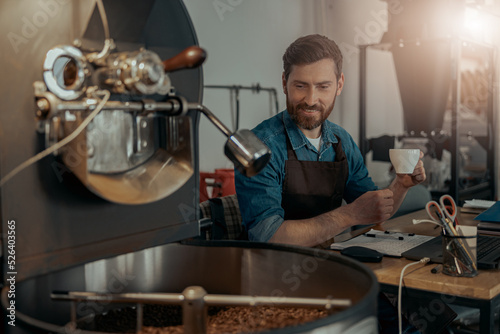 Business owner of coffee roasting factory working and drinking coffee