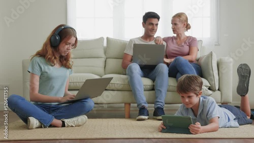Happy family using multiple digital devices, laptops and tablet together in living room.