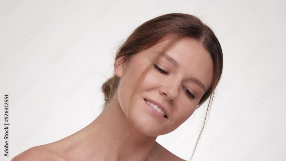 Beautiful female with fresh glowing hydrated facial skin and natural makeup on light background at studio. Skin care concept. Pretty Beauty face. Caucasian young woman look at the camera and smiling. Beautiful female with fresh glowing hydrated facial skin and natural makeup on light background at studio. Skin care concept. Pretty Beauty face. Caucasian young woman look at the camera and smiling.